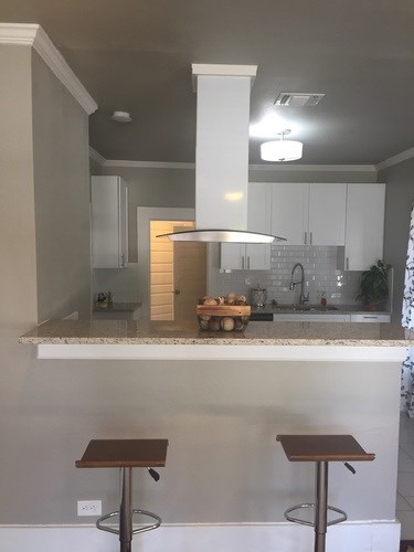 A kitchen with a marble countertop and a bar stool.