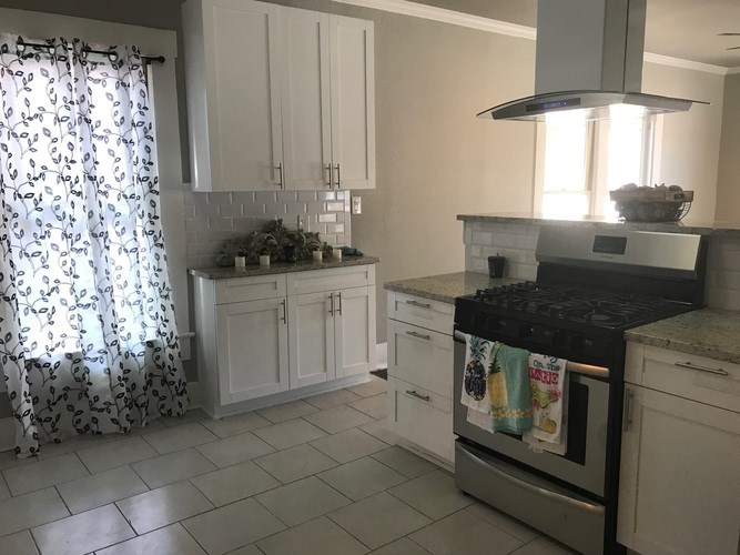 A kitchen with white cabinets and a black stove top.