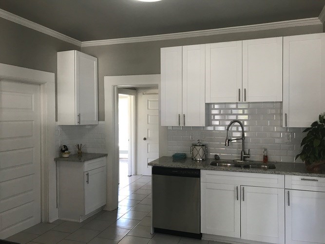 A kitchen with white cabinets and a black dishwasher.