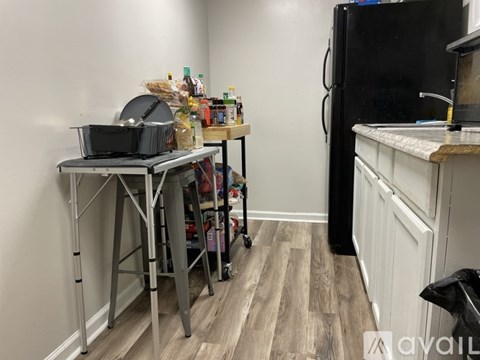 A kitchen with a black fridge and a table with a grill on it.