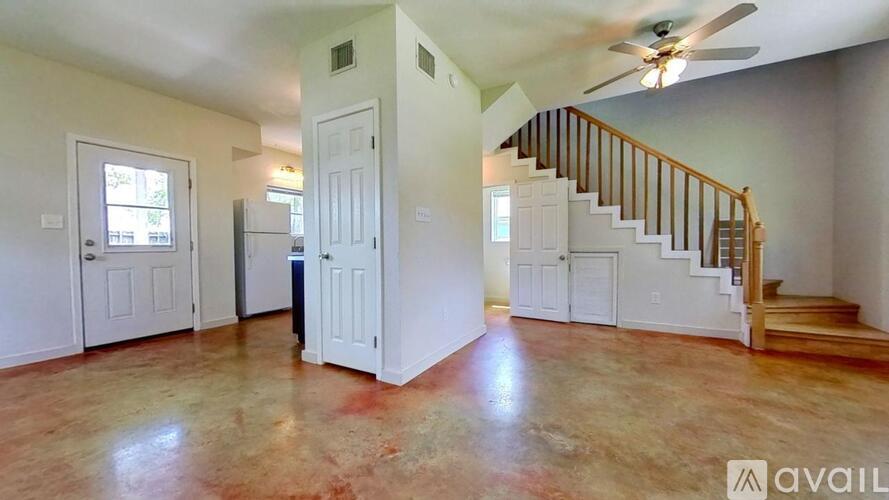 A spacious room with a staircase and a ceiling fan.
