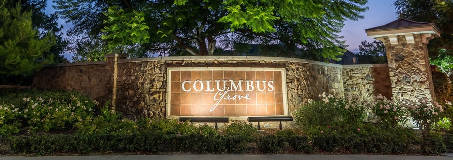 A sign that says Columbus Ave is lit up at night.