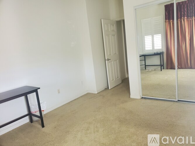 A room with a carpeted floor and a sliding glass door leading to a balcony.