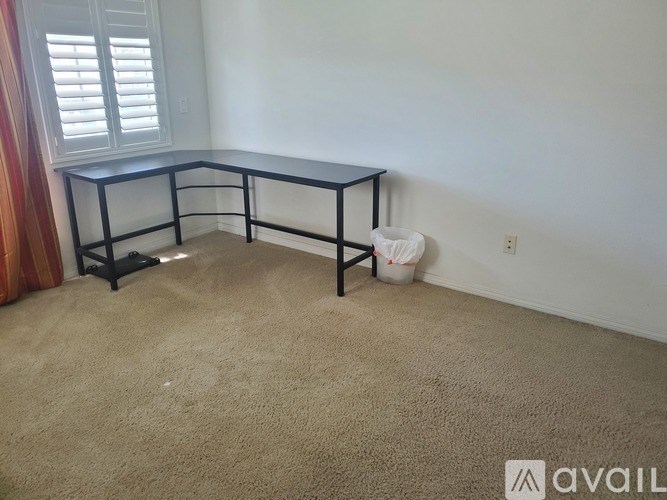 A black desk with a white bucket on the floor.
