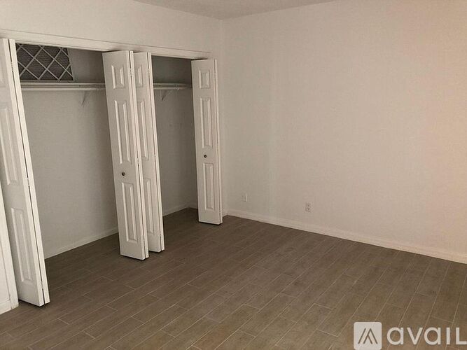 A room with two open closets and a wooden floor.