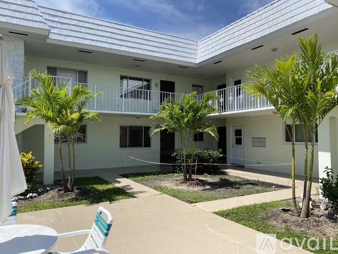 A white building with a balcony and a green chair in front.
