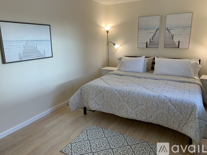 A bedroom with a bed, two pictures on the wall, and a lamp.