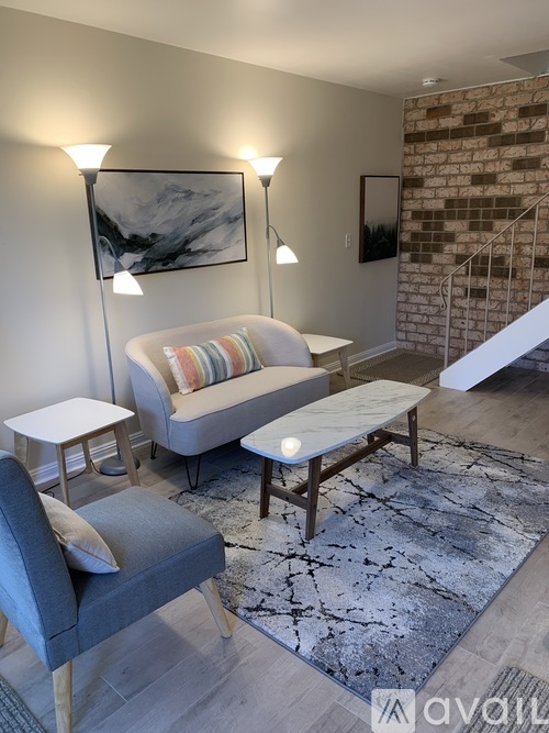 A living room with a grey sofa, a white armchair, a wooden coffee table, and a grey chair with a white cushion.