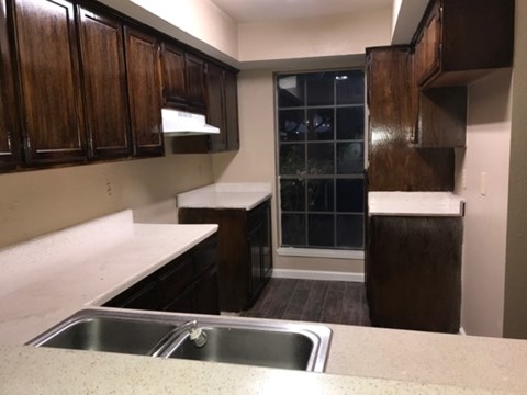 A kitchen with wooden cabinets and a stainless steel sink.