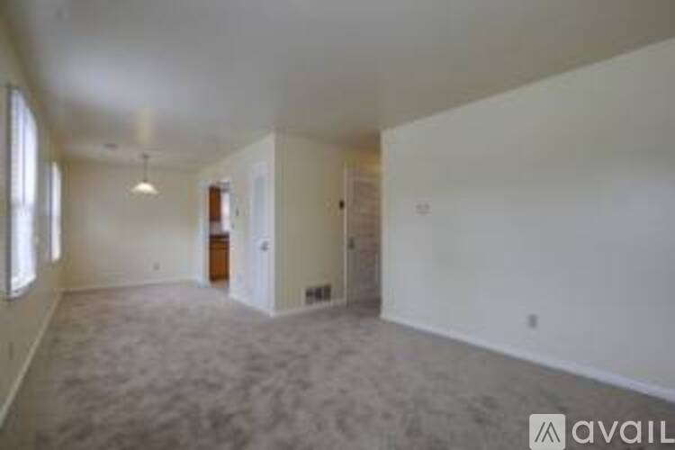 A spacious empty room with carpeted floor and white walls.