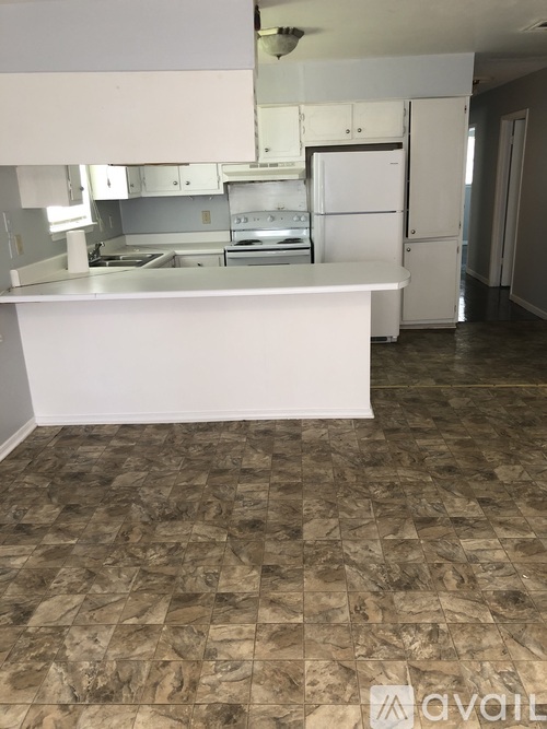 A kitchen with a white counter and brown tiled floor.