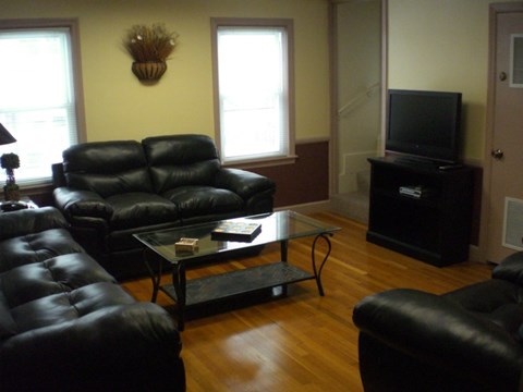A living room with black leather furniture and a flat screen TV.