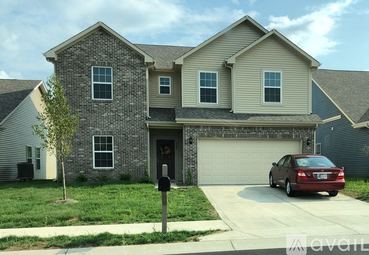 A two-story house with a garage and a car parked in front.
