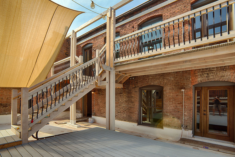 A wooden staircase with a yellow awning is in front of a brick building.