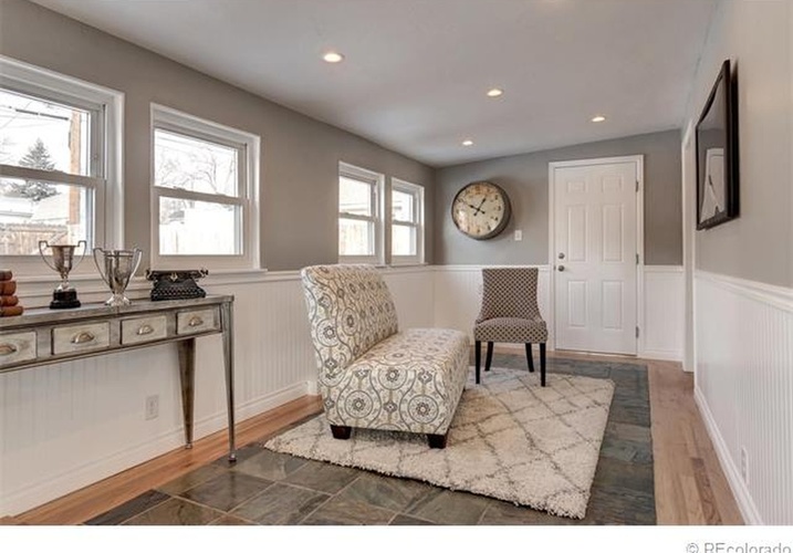 A living room with a patterned chair and a clock on the wall.