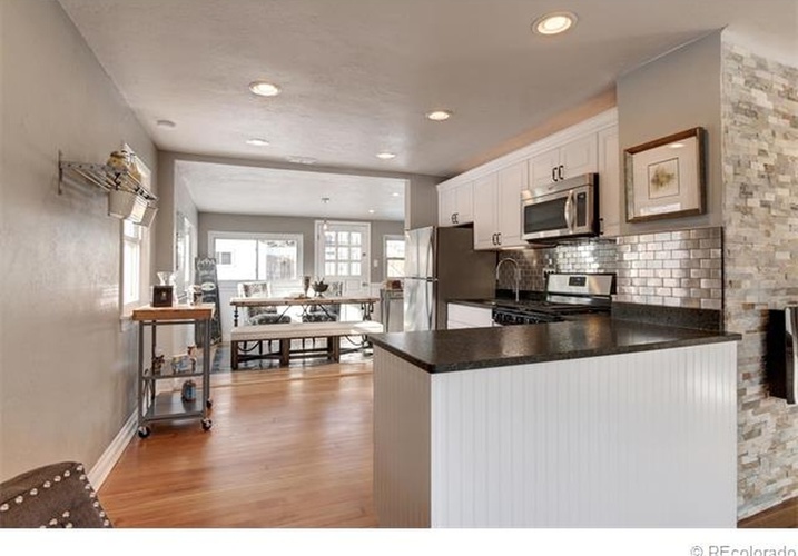 A kitchen with a white counter and a brick wall.