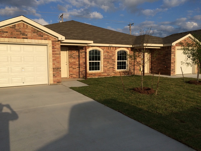 A house with a driveway and a tree in front.