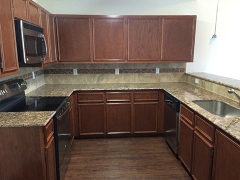 A kitchen with brown cabinets and granite countertops.