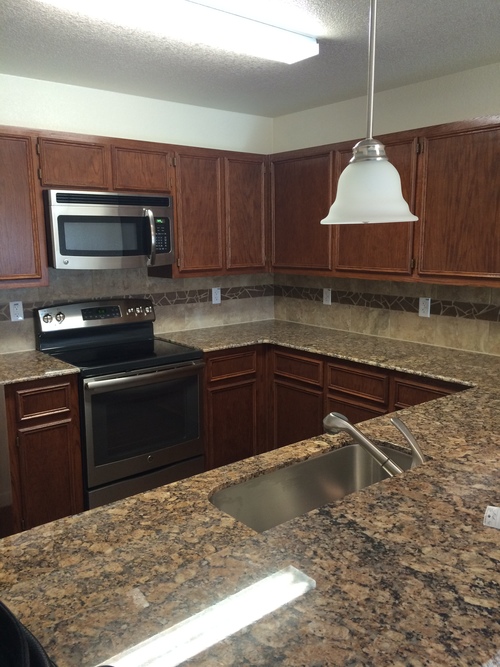 A kitchen with granite countertops and wooden cabinets.