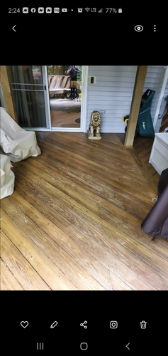 A wooden floor in a room with a white door and a green trash can.