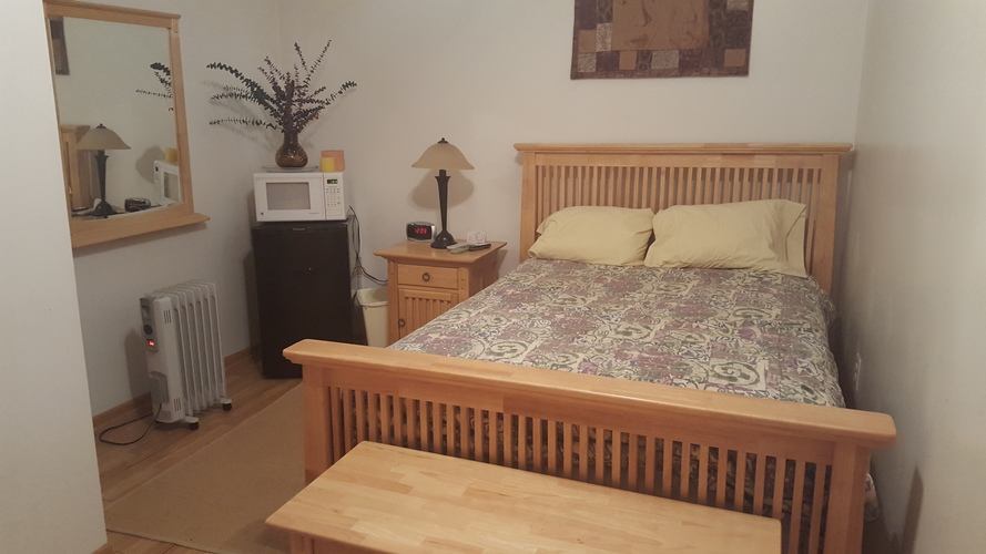A bedroom with a bed, nightstand, and a heater.