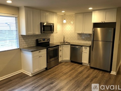 A kitchen with white cabinets and a wooden floor.
