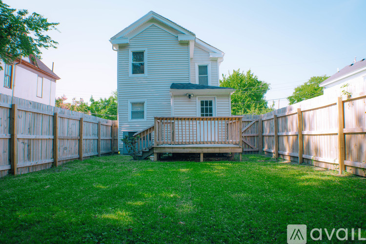 A house with a white fence and a deck in the backyard.
