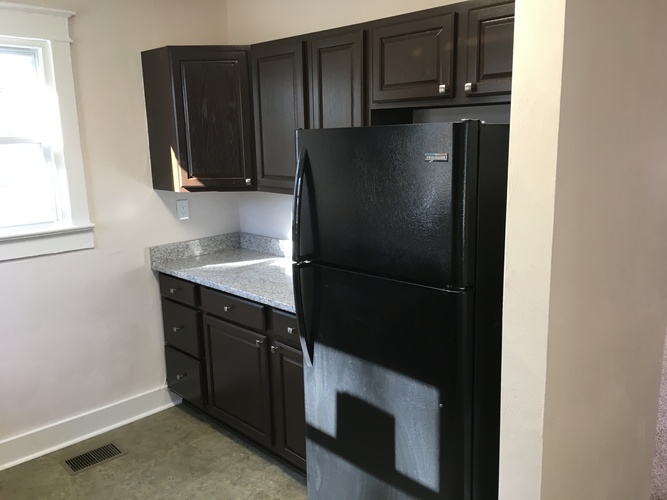 A black fridge in a kitchen with black cabinets.