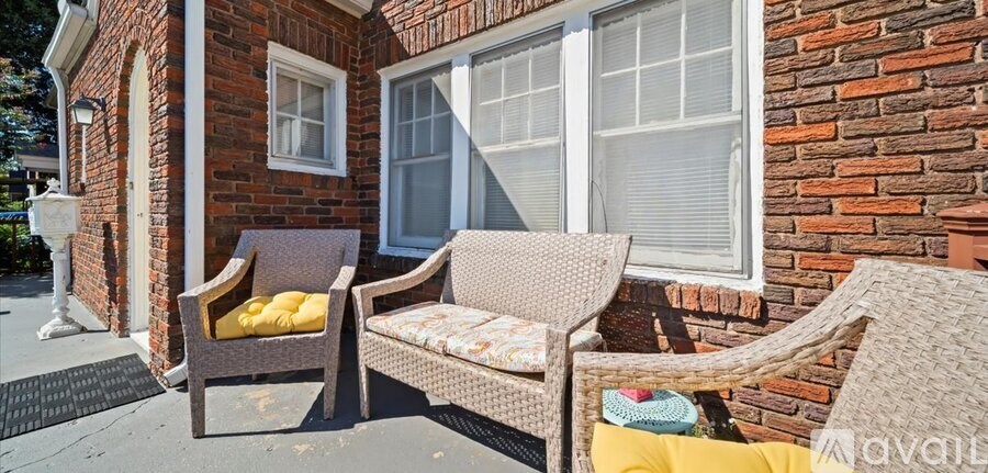 Two wicker chairs with cushions are placed on a porch.