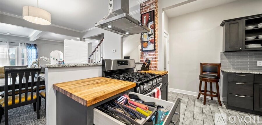 A kitchen with a wooden island and a brick accent wall.