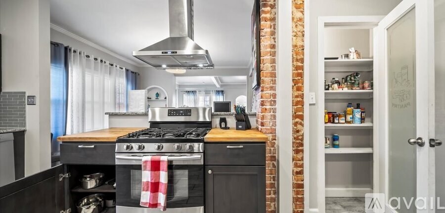 A kitchen with a stove top oven and a brick wall.