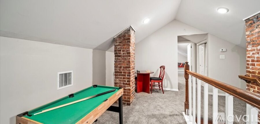 A pool table in a room with a brick pillar.