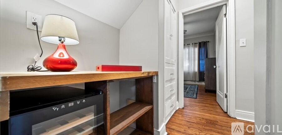 A red lamp sits on a wooden shelf next to a black oven.