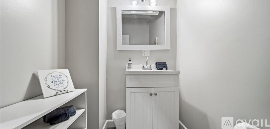 A bathroom with a white cabinet and a mirror above it.
