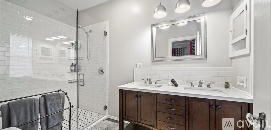 A bathroom with a walk-in shower and double sinks.