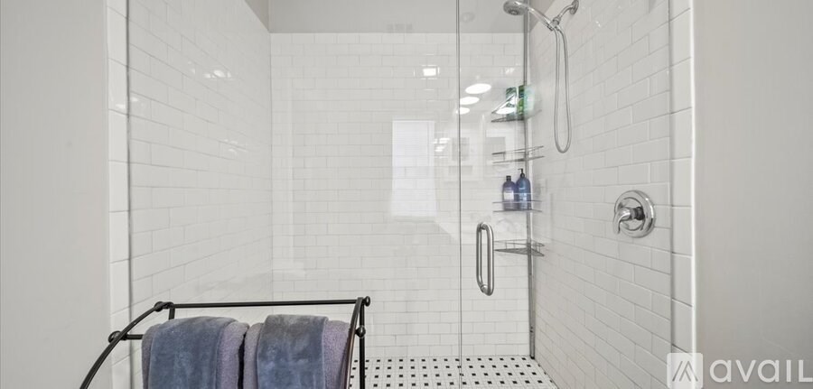 A shower area with a glass door and a rack of towels.