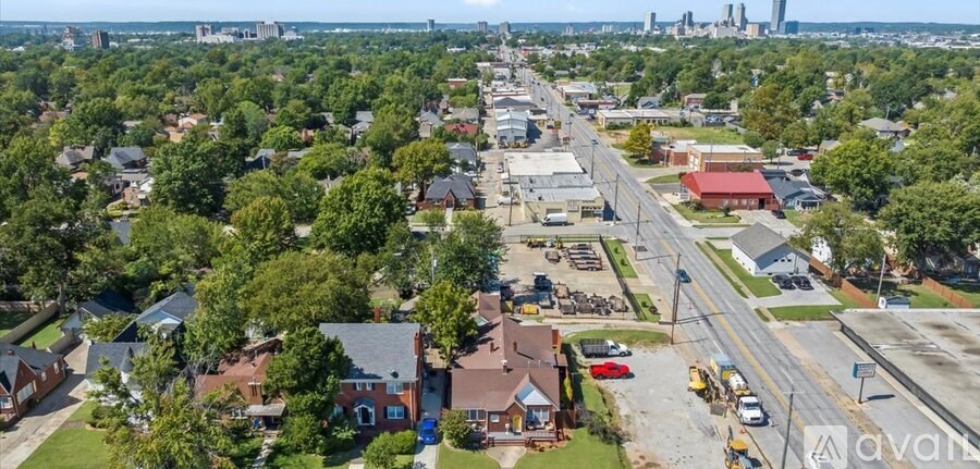 A bird's eye view of a residential area with houses, trees, and a road.