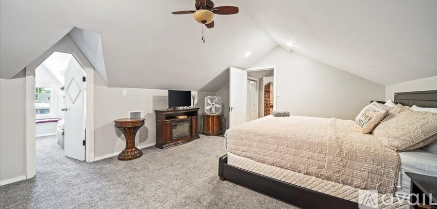 A bedroom with a bed, a television, and a ceiling fan.