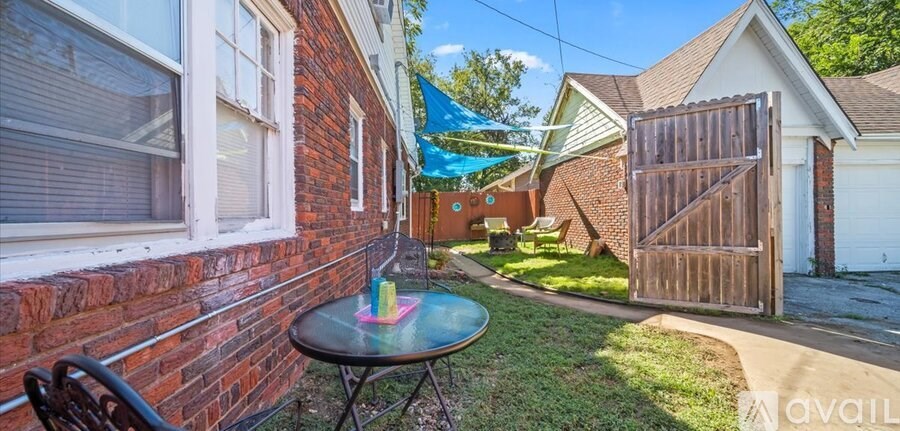 A patio with a table and chairs is in front of a brick house.