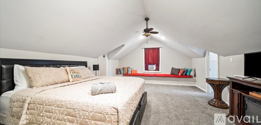 A bedroom with a large bed and a window with red curtains.