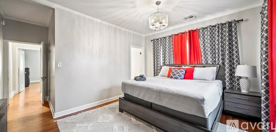 A bedroom with a large bed and a red curtain.