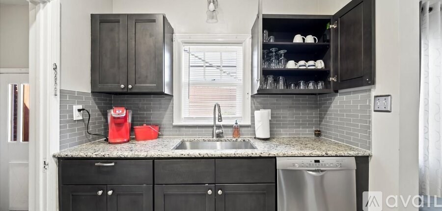 A kitchen with black cabinets and a white sink.