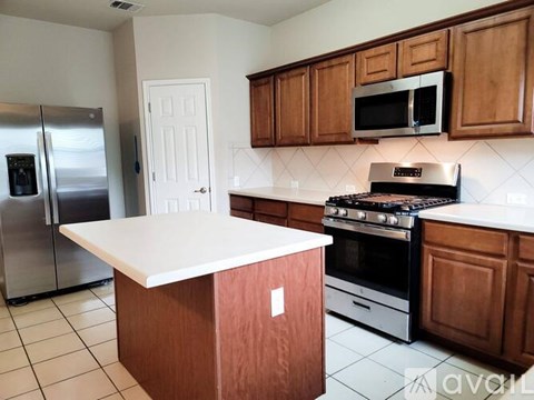 A kitchen with a white counter top and wooden cabinets.