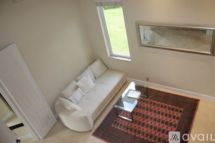 A white couch with a red rug in front of it.