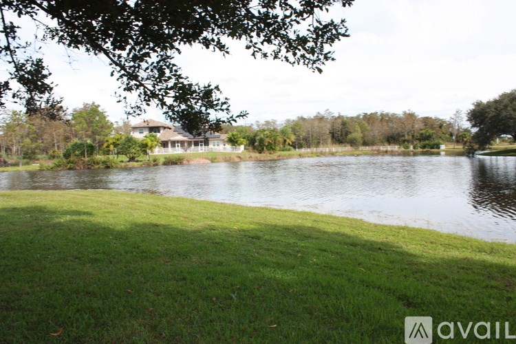 A grassy area with a body of water and a house in the background.
