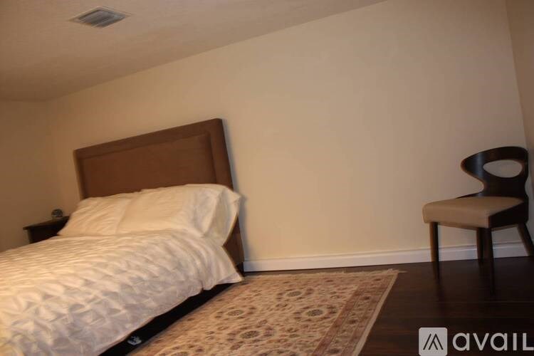 A bedroom with a bed, chair, and rug.