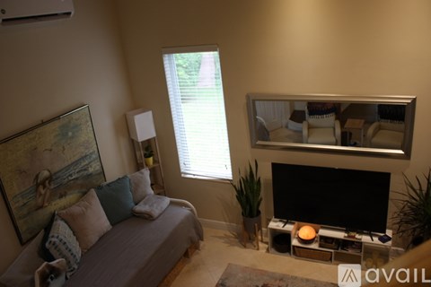 A living room with a grey couch, a television, and a large painting on the wall.