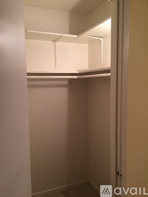 A small, empty room with a white door and a white shelf above it.