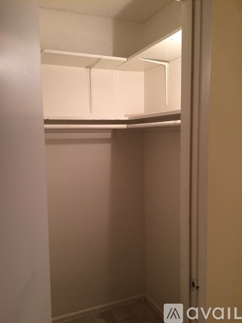 A small, empty room with a white door and a white shelf above it.