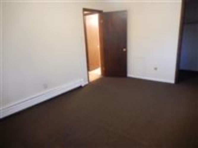 A room with a brown door and white walls.
